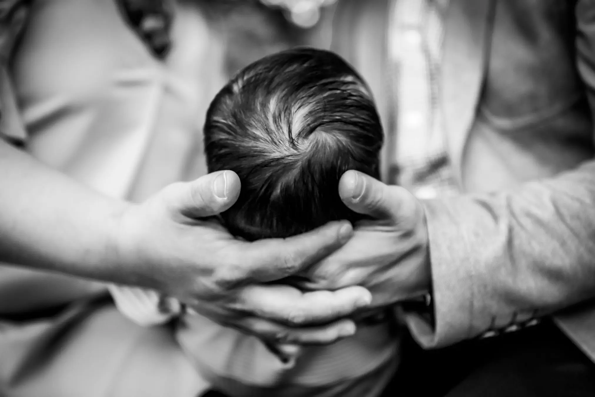 newborn photo session with parents cradling infant's head in BW