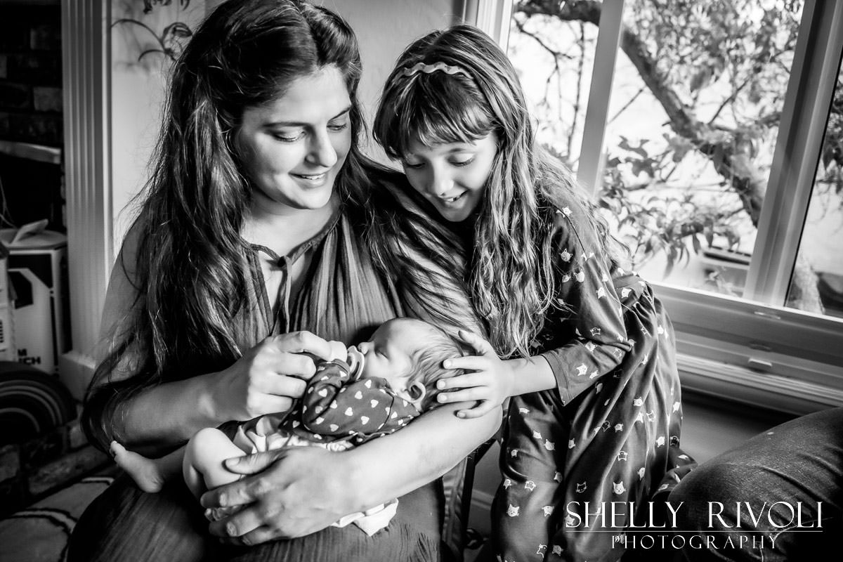 Mom and big sister admire newborn baby during in-home newborn photo session by Shelly Rivoli