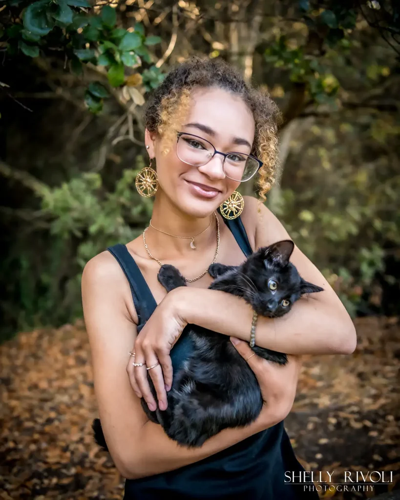 Outdoor senior portrait of young woman holding pet cat by editorial